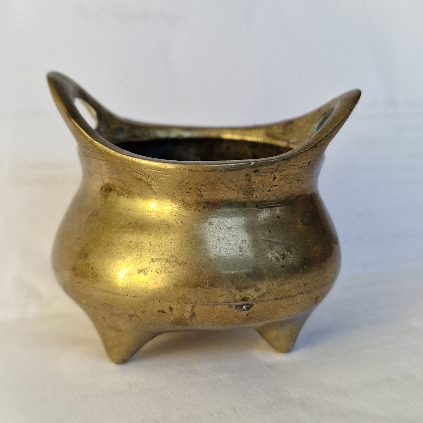 A Chinese bronze tripod censer, of typical shallow rounded form, supported on three short legs, the base with an apocryphal character mark