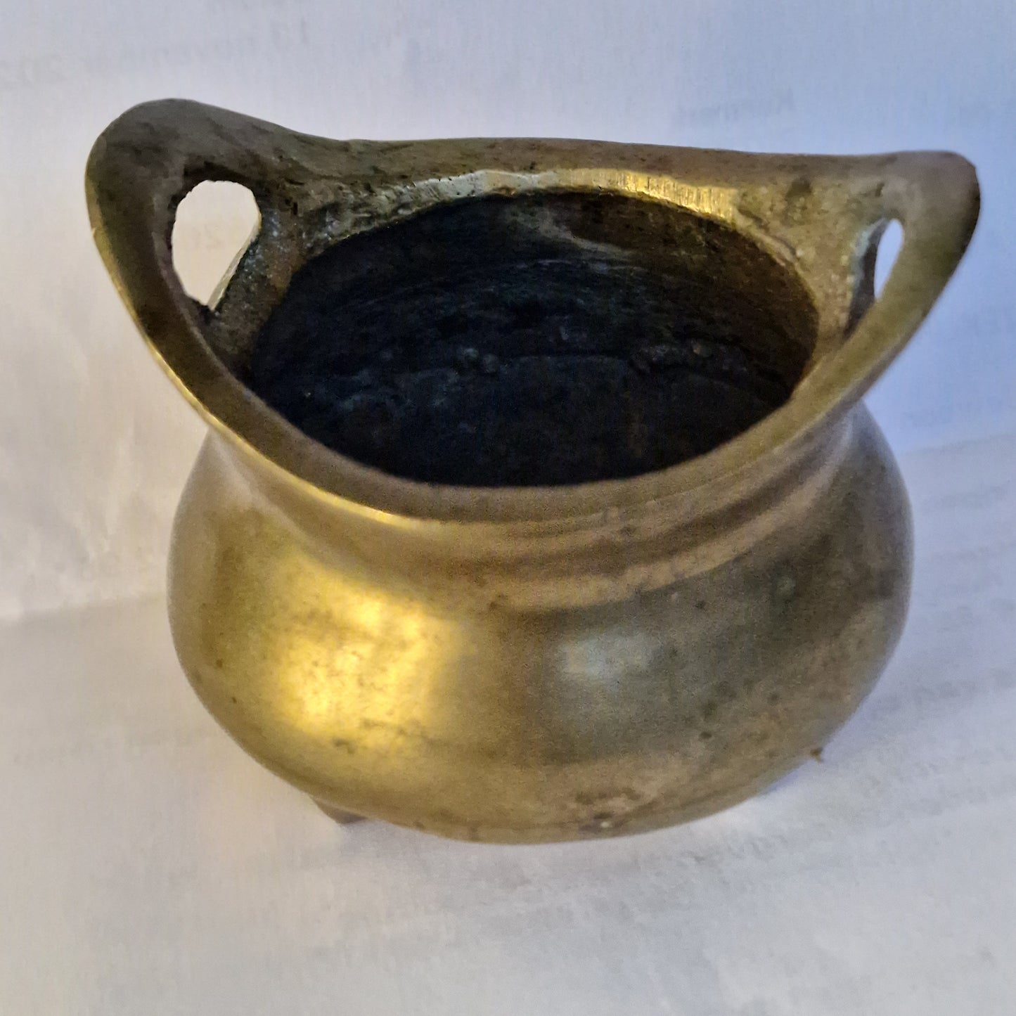 A Chinese bronze tripod censer, of typical shallow rounded form, supported on three short legs, the base with an apocryphal character mark