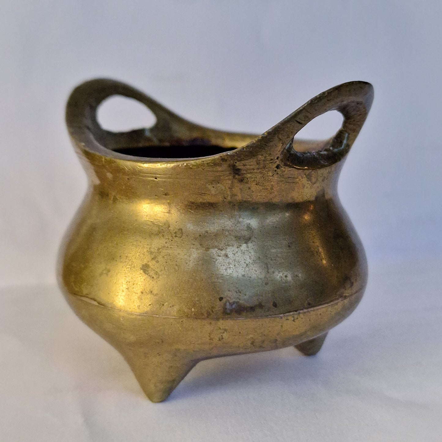 A Chinese bronze tripod censer, of typical shallow rounded form, supported on three short legs, the base with an apocryphal character mark