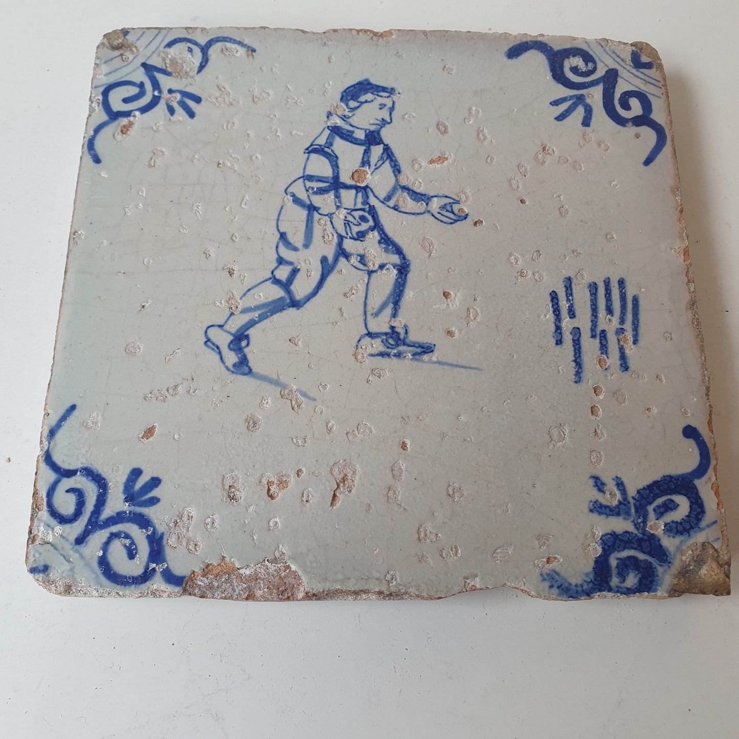 Nederlands antiek - tegel :kinderspel , gedecoreerd met een ossenkop hoekmotief - gedateerd  1640