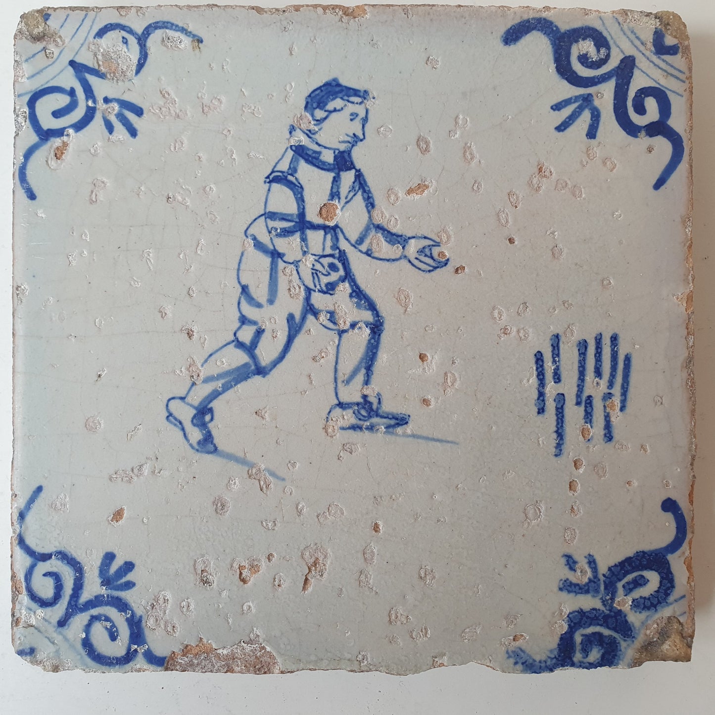 Nederlands antiek - tegel :kinderspel , gedecoreerd met een ossenkop hoekmotief - gedateerd  1640