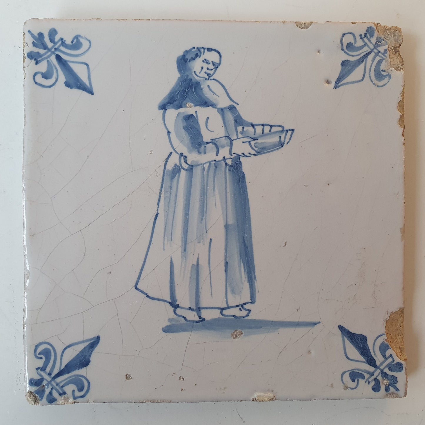 Nederlands antiek - tegel marktkoopvrouw , gedecoreerd met een lelie hoekmotief - gedateerd  1640