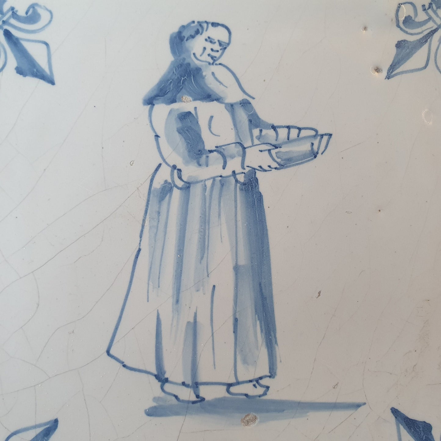 Nederlands antiek - tegel marktkoopvrouw , gedecoreerd met een lelie hoekmotief - gedateerd  1640