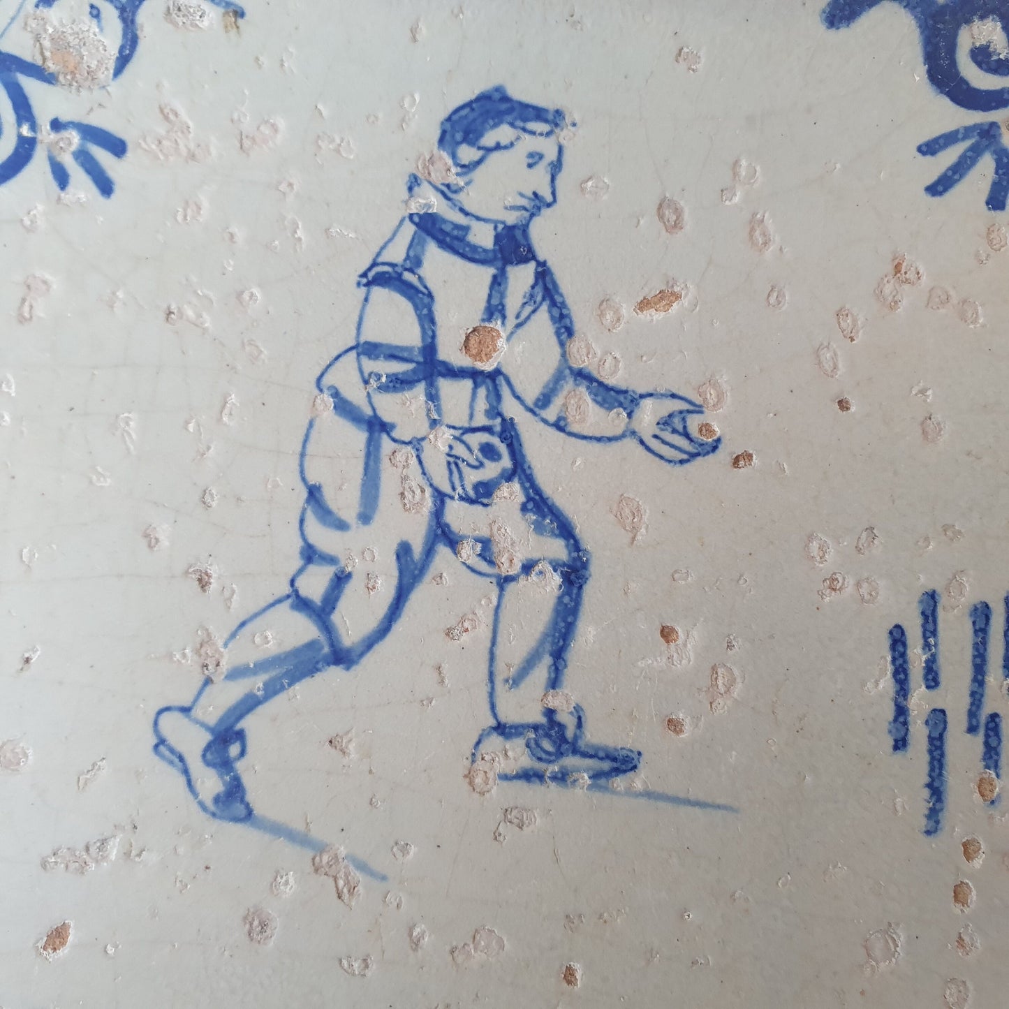 Nederlands antiek - tegel :kinderspel , gedecoreerd met een ossenkop hoekmotief - gedateerd  1640