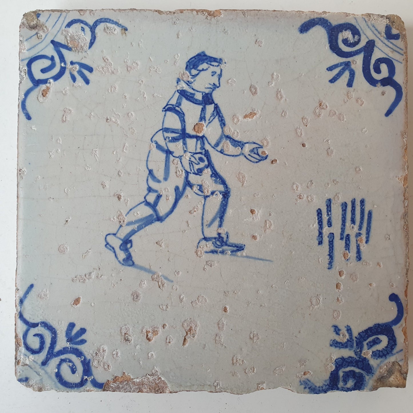 Nederlands antiek - tegel :kinderspel , gedecoreerd met een ossenkop hoekmotief - gedateerd  1640