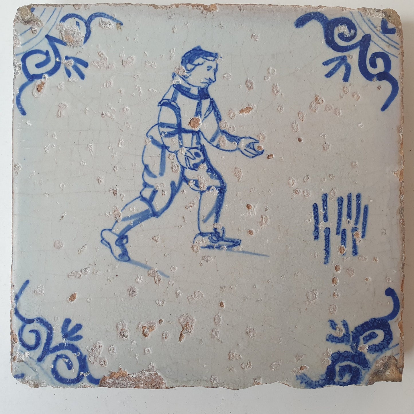 Nederlands antiek - tegel :kinderspel , gedecoreerd met een ossenkop hoekmotief - gedateerd  1640