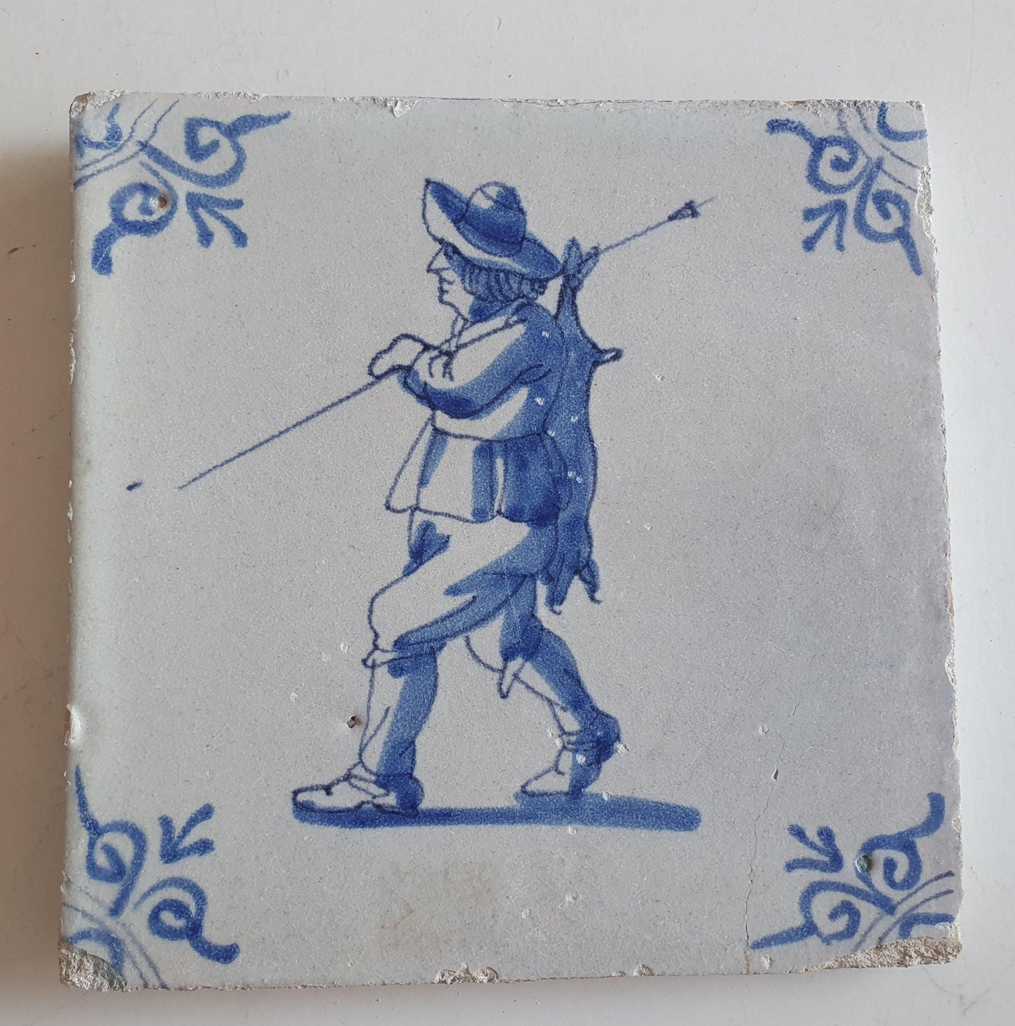 Dutch antique tile, 17th century, hunter with hare on his back, oxhead corner Rare !