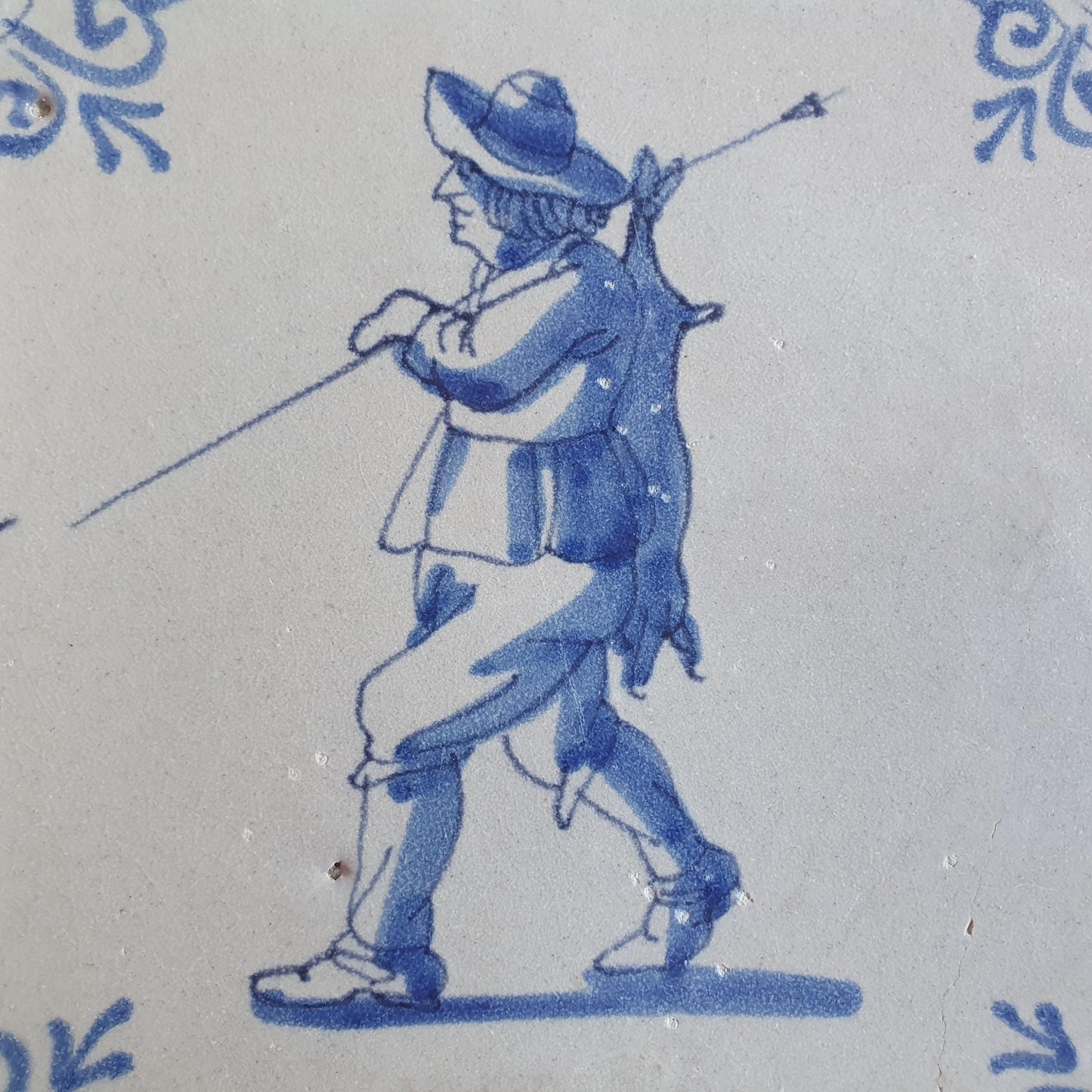 Dutch antique tile, 17th century, hunter with hare on his back, oxhead corner Rare !