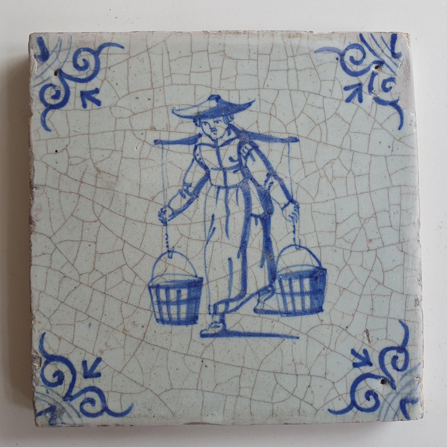 17th Delft tile was  made around 1650 and depicts a woman with buckets