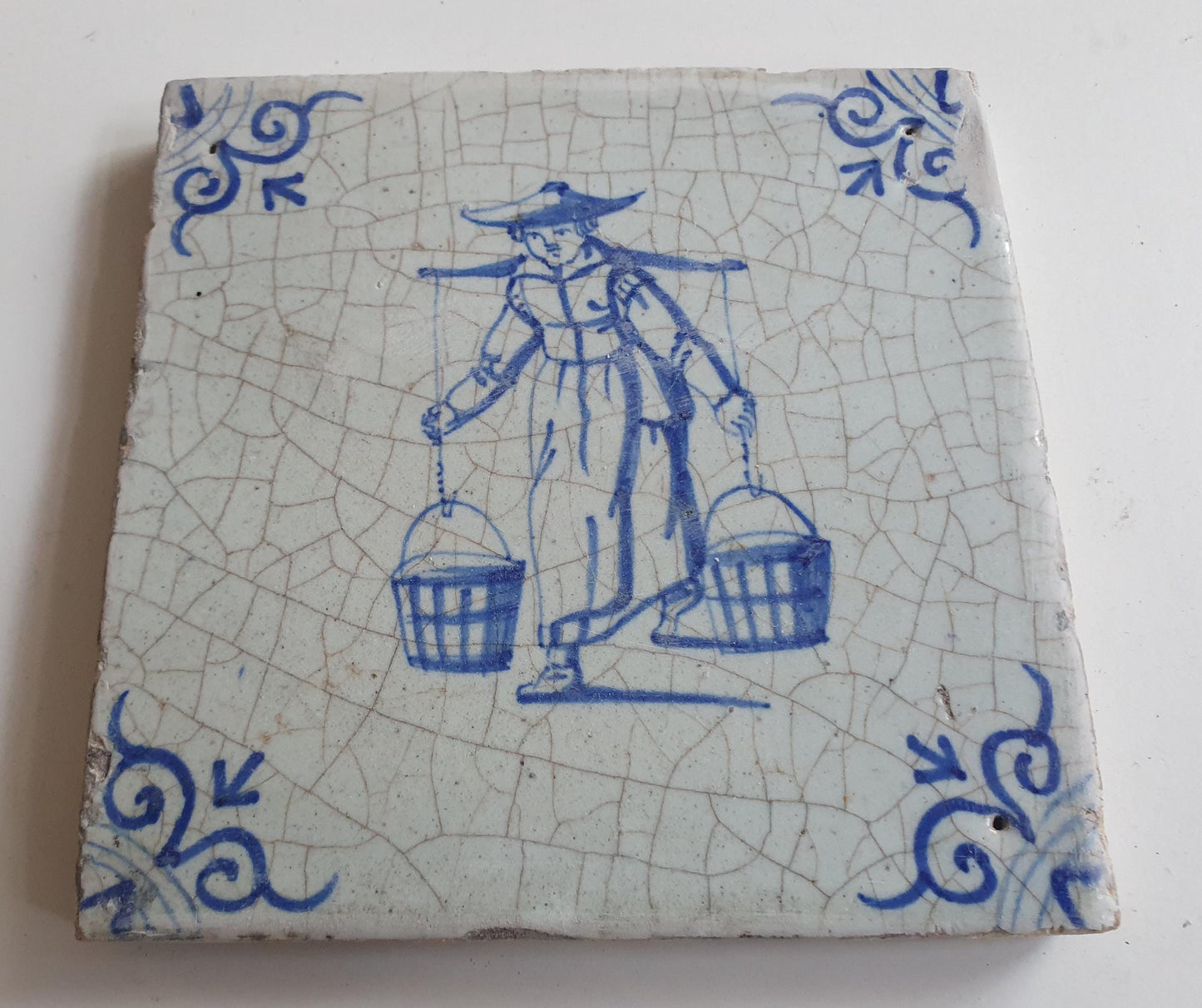 17th Delft tile was  made around 1650 and depicts a woman with buckets