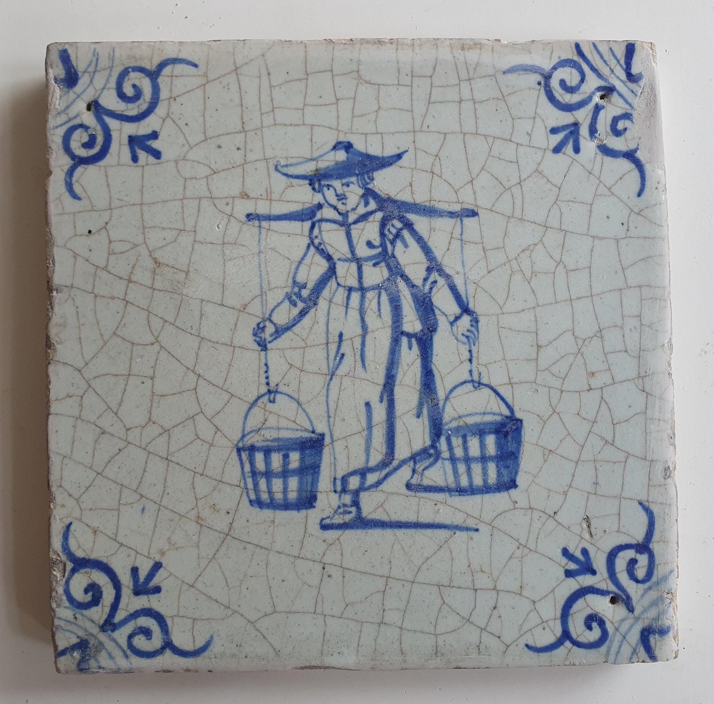 17th Delft tile was  made around 1650 and depicts a woman with buckets
