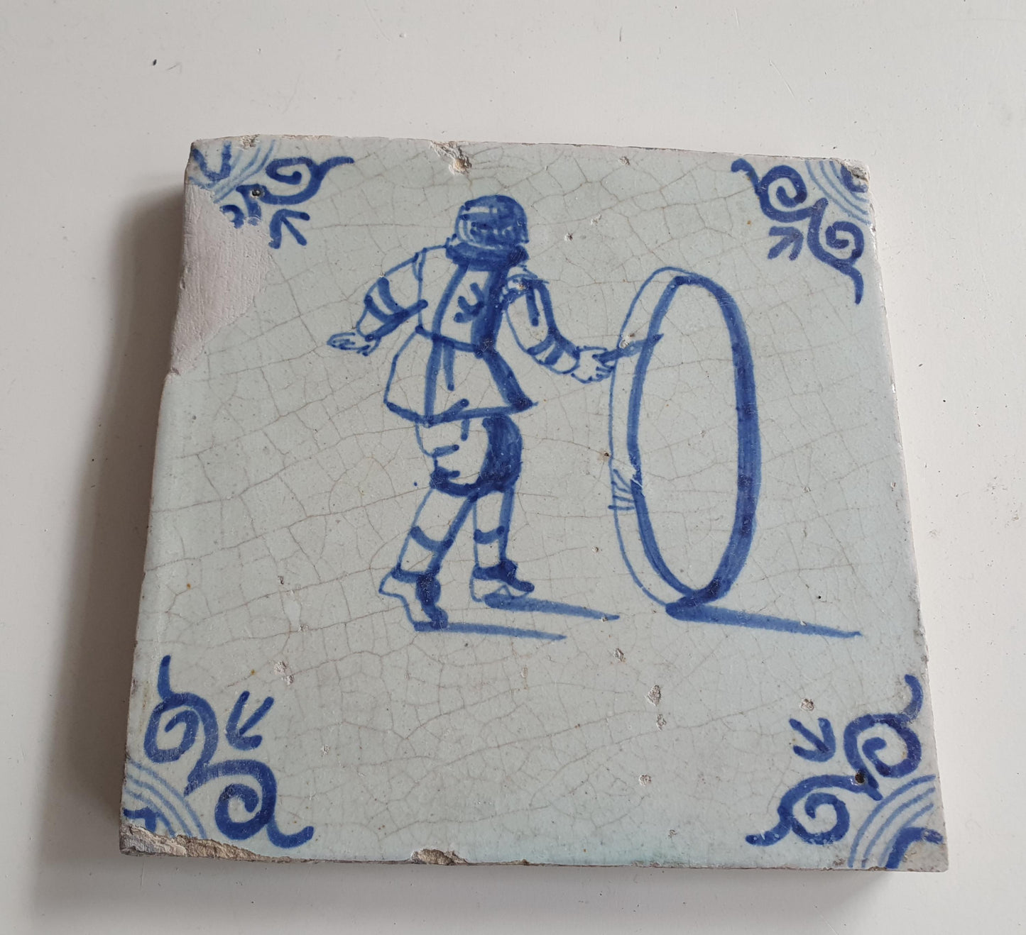 17th Delft tile was  made around 1650 and depicts a  child with a  hoop
