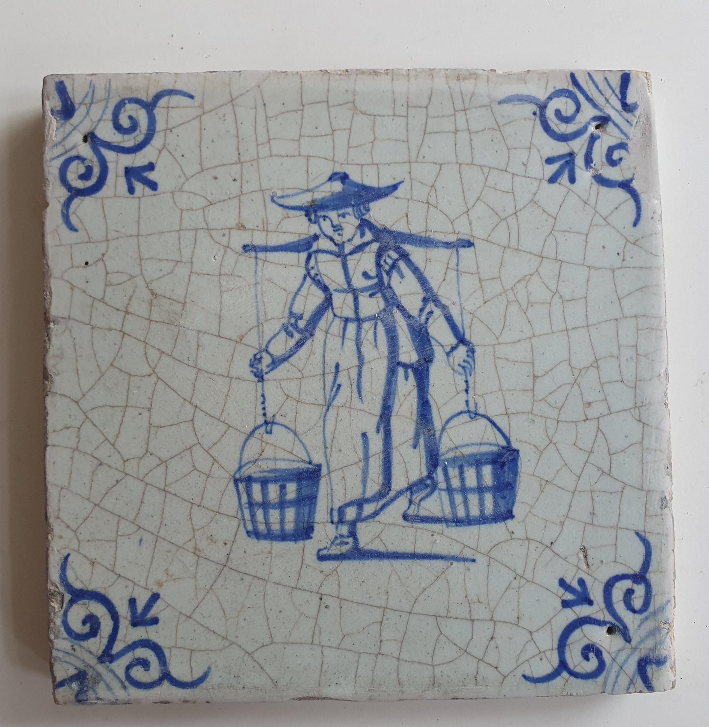 17th Delft tile was  made around 1650 and depicts a woman with buckets