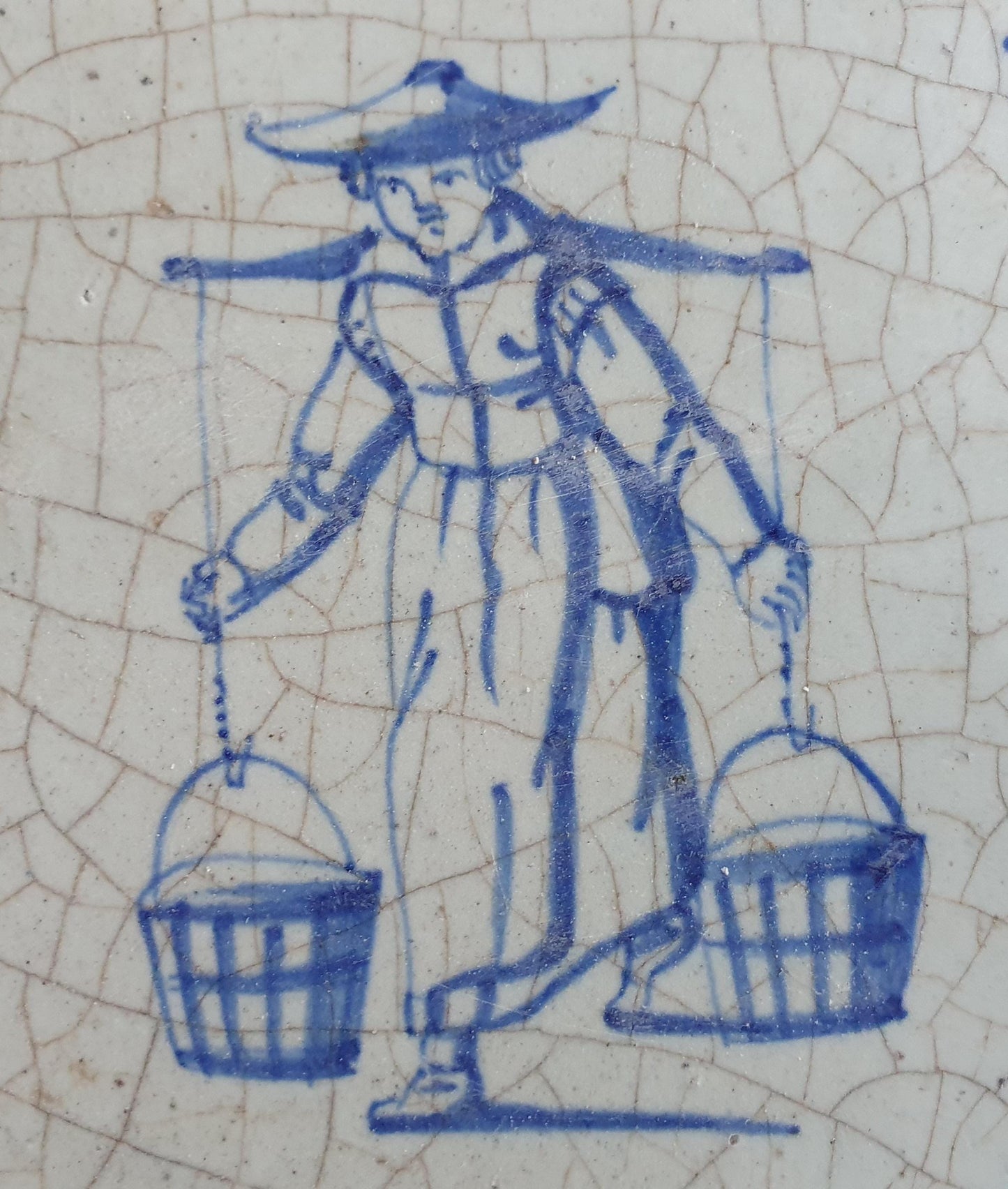 17th Delft tile was  made around 1650 and depicts a woman with buckets