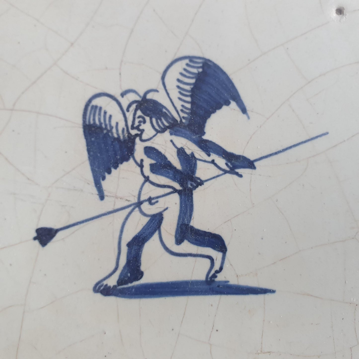 This antique Delft tile, dating from around 1640, depicts Cupid with stick.
