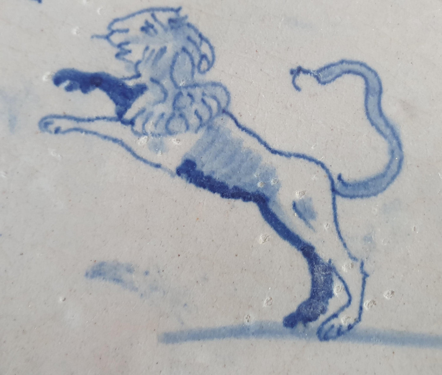 This 17th century Delft tile depicts a leaping lion, delicately painted in blue