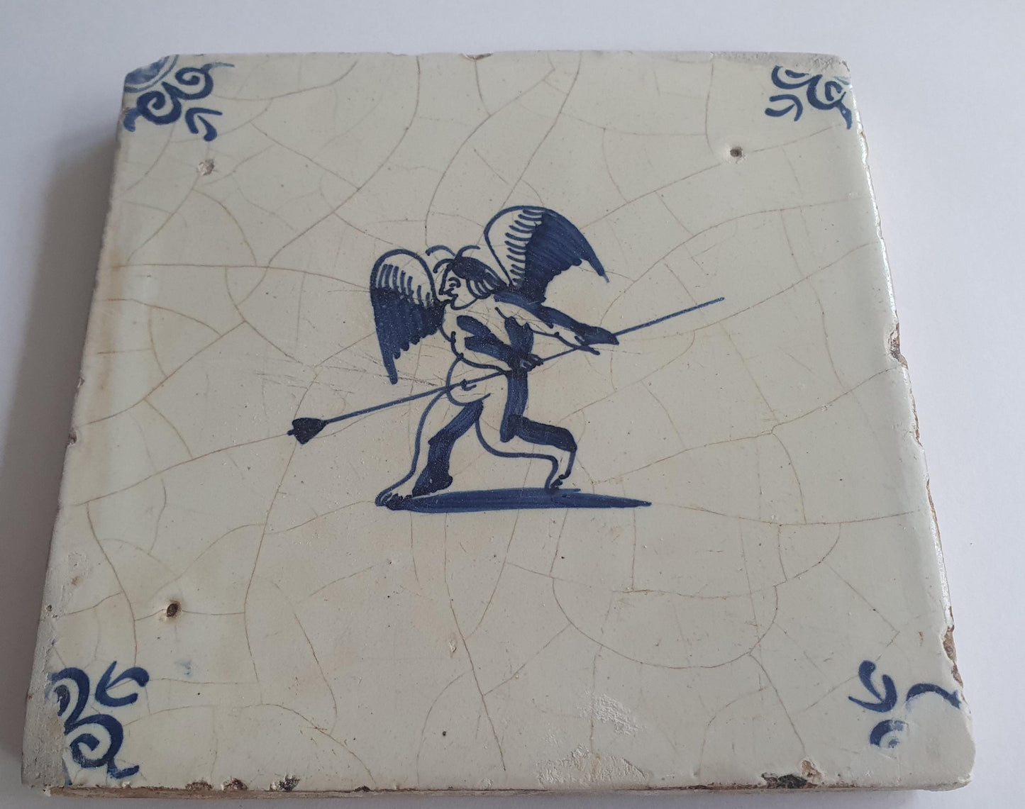 This antique Delft tile, dating from around 1640, depicts Cupid with stick.