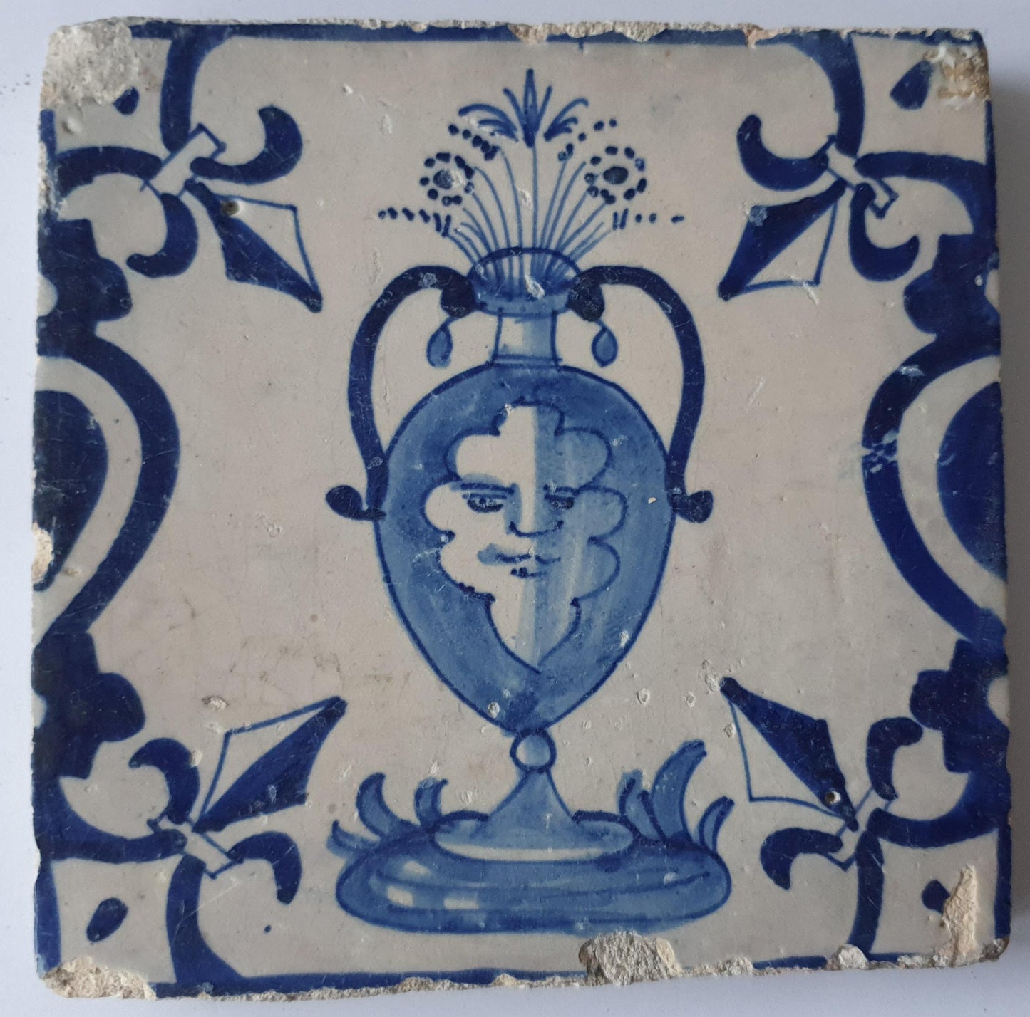 This rare antique Delft tile depicts a flowerpot in blue with face.     around  1620