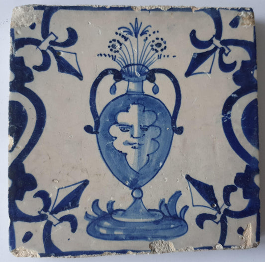 This rare antique Delft tile depicts a flowerpot in blue with face.     around  1620