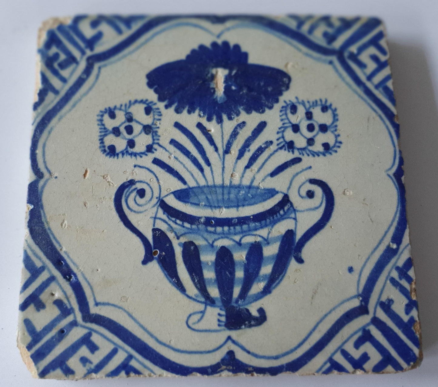 This antique Delft tile from the 17th century features a vase of flowers  1620- 1640