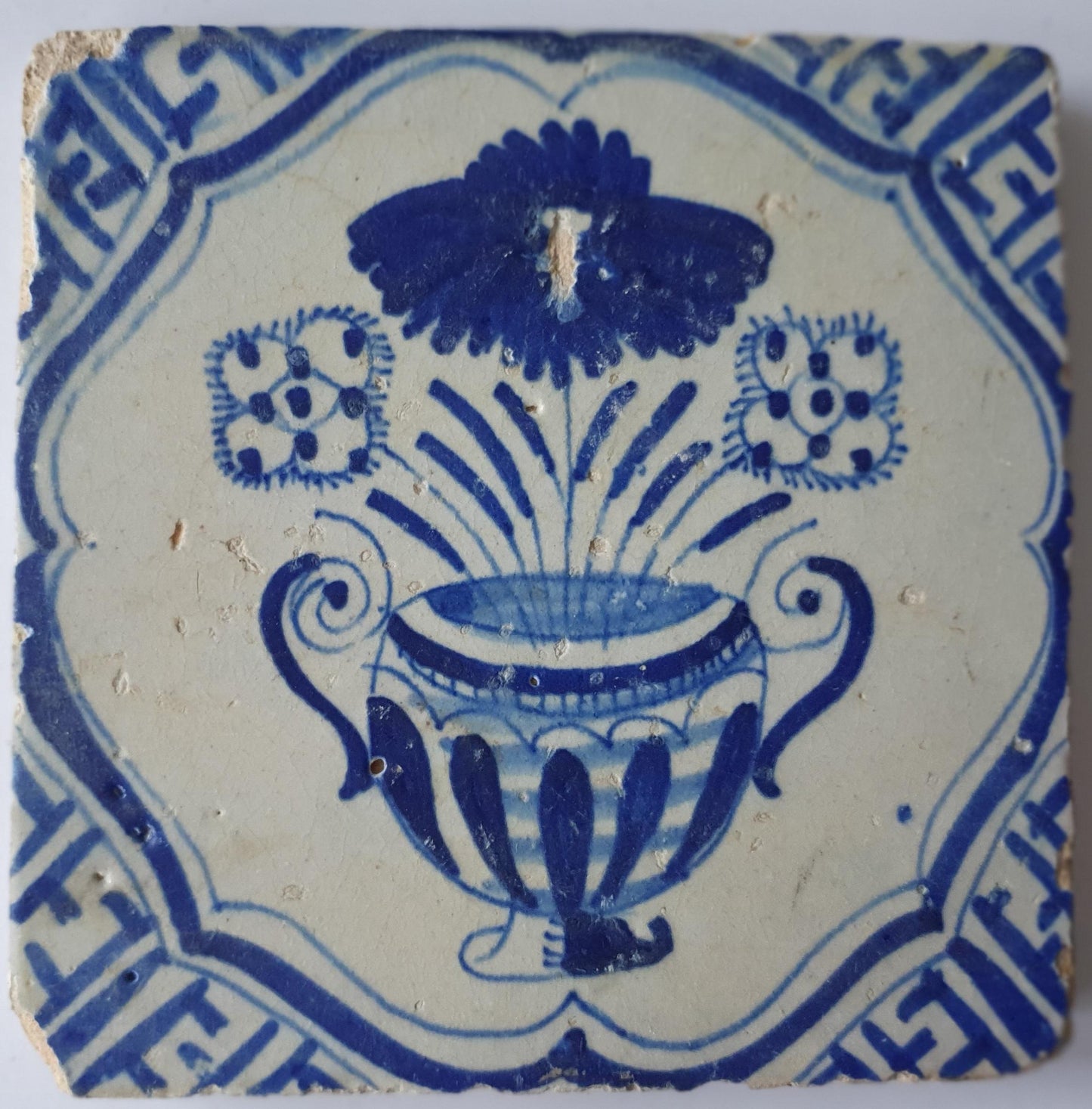 This antique Delft tile from the 17th century features a vase of flowers  1620- 1640