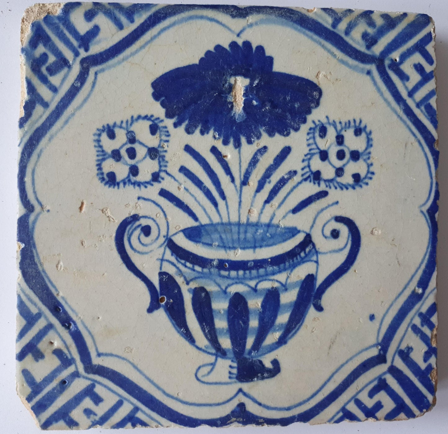 This antique Delft tile from the 17th century features a vase of flowers  1620- 1640