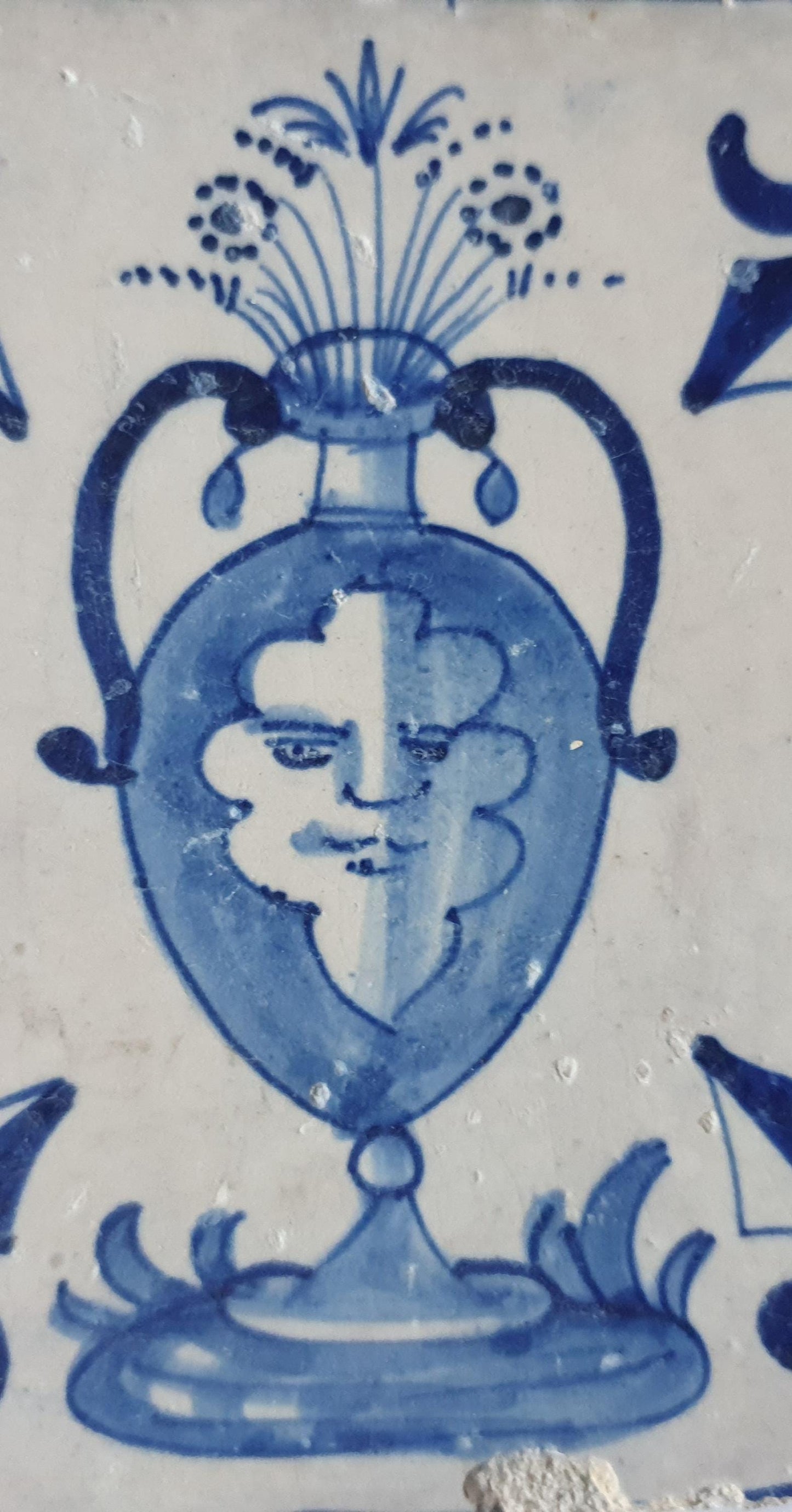 This rare antique Delft tile depicts a flowerpot in blue with face.     around  1620