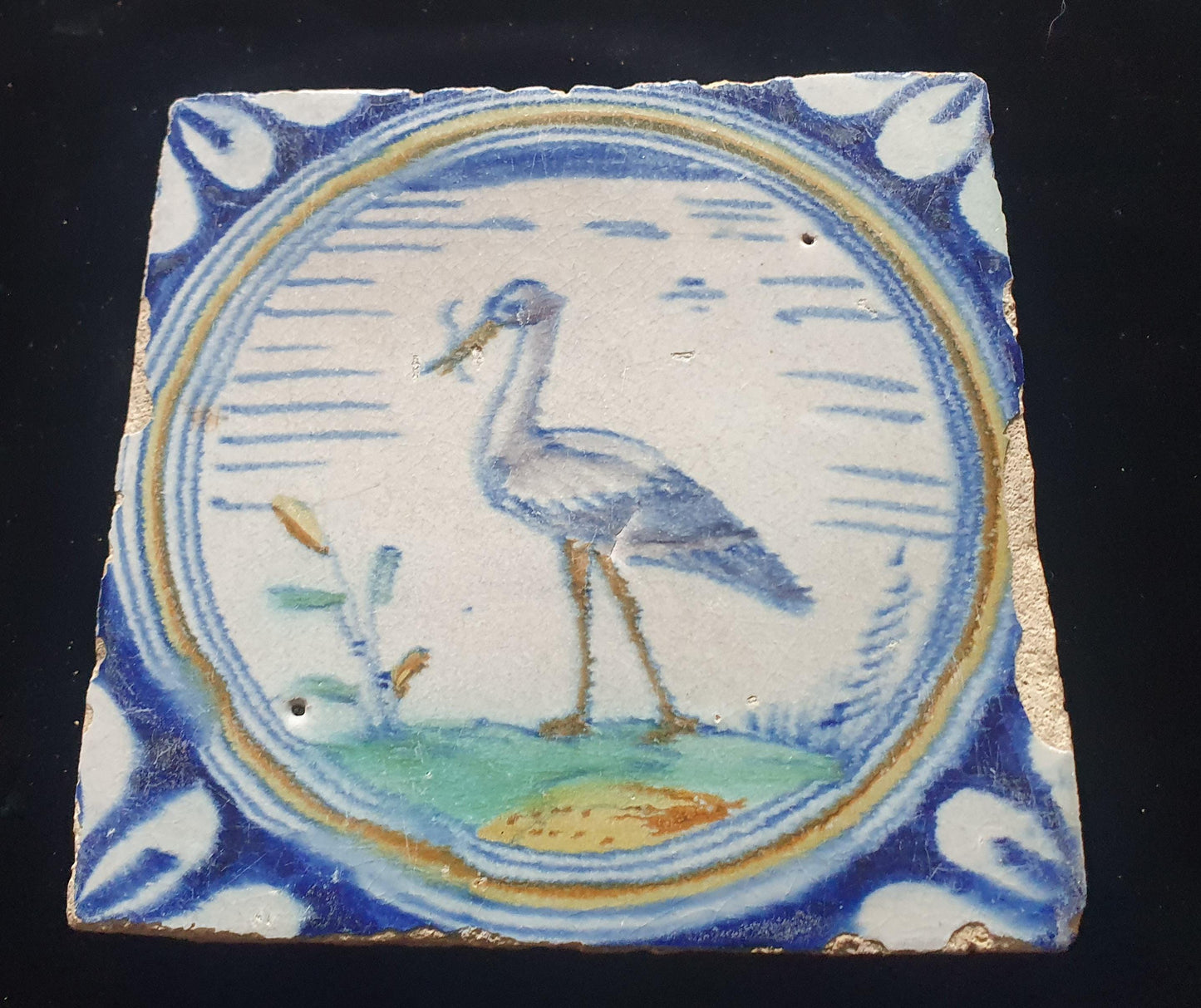 Deze zeldzame Delftse tegel uit de 17e eeuw, beschilderd rond 1620, toont een ooiervaar met in zijn bek een paling. ;  verzameltegel.