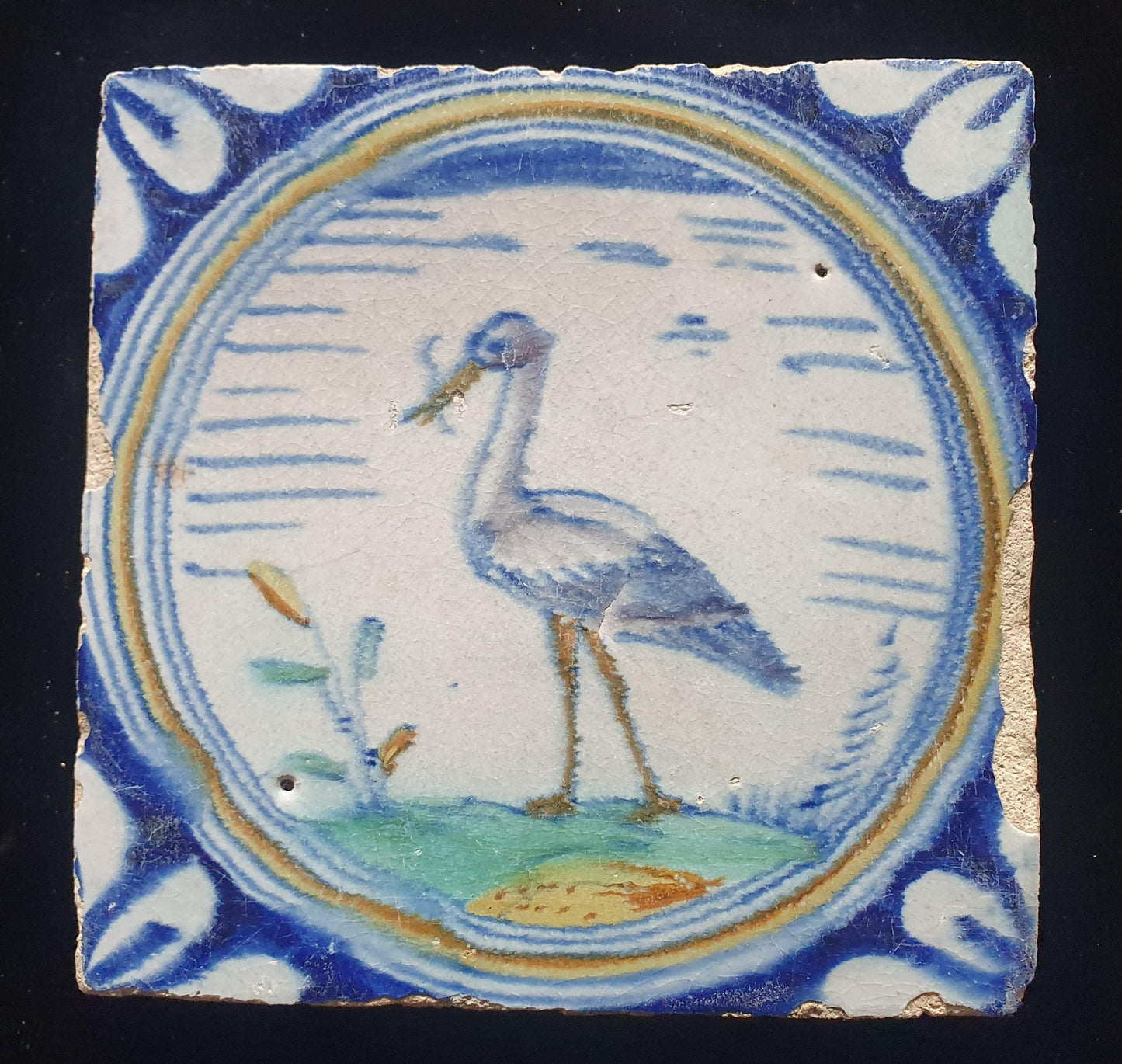 Deze zeldzame Delftse tegel uit de 17e eeuw, beschilderd rond 1620, toont een ooiervaar met in zijn bek een paling. ;  verzameltegel.