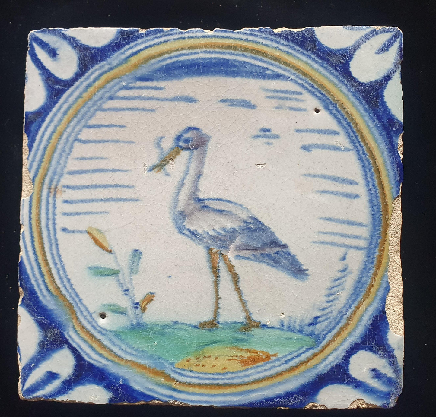Deze zeldzame Delftse tegel uit de 17e eeuw, beschilderd rond 1620, toont een ooiervaar met in zijn bek een paling. ;  verzameltegel.
