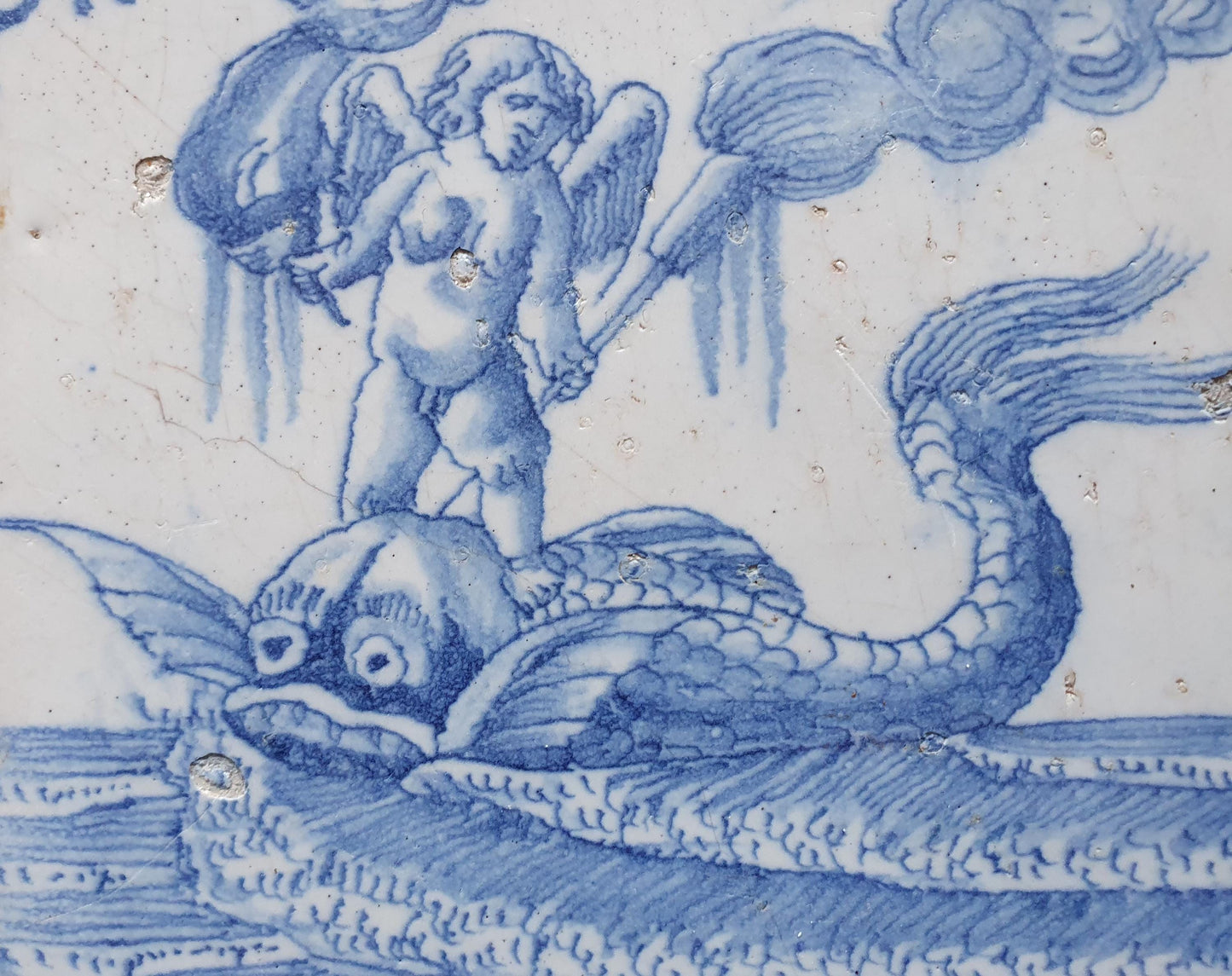 Deze antieke Delftse tegel dateert van rond 1670 en toont een putti op een monsterachtige dolfijn staat, verzameltegel.