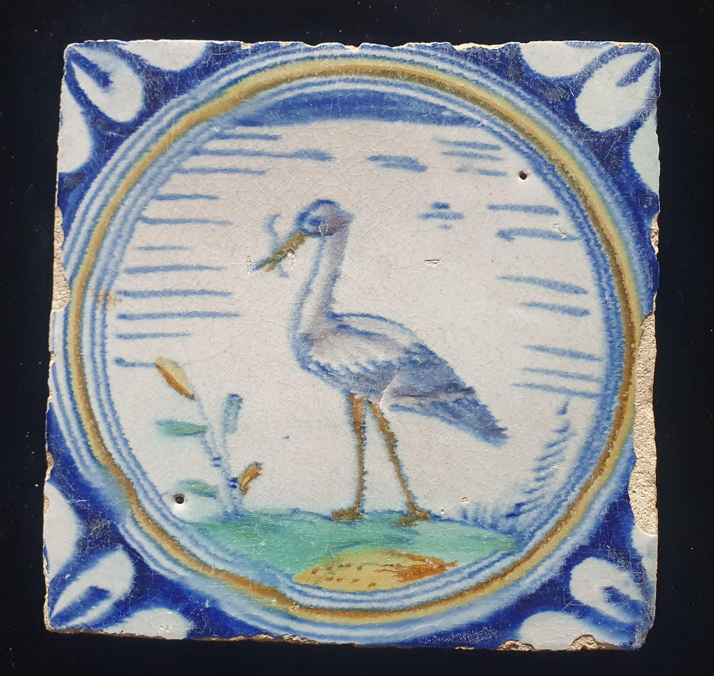 Deze zeldzame Delftse tegel uit de 17e eeuw, beschilderd rond 1620, toont een ooiervaar met in zijn bek een paling. ;  verzameltegel.
