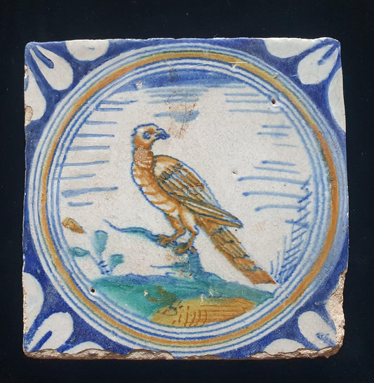 Deze zeldzame Delftse tegel uit de 17e eeuw, beschilderd rond 1620, toont een  roofvogel op een tak . ;  verzameltegel.