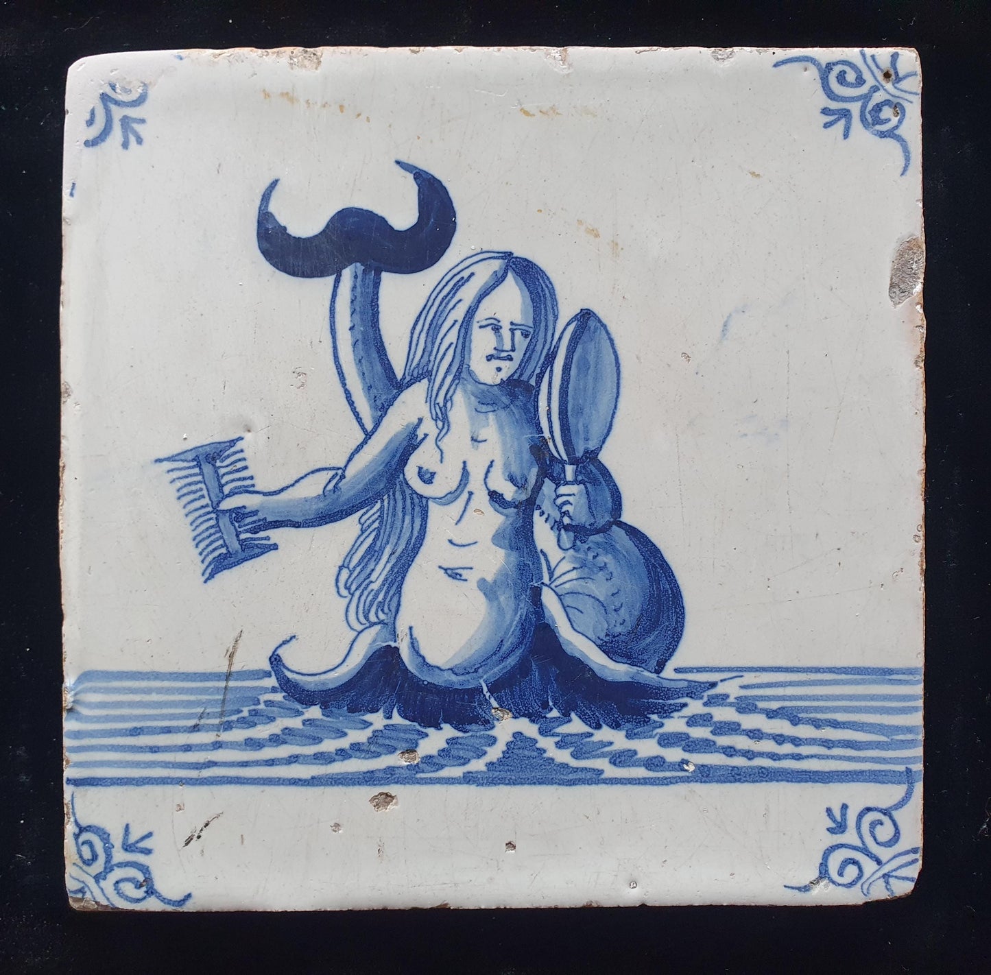 Delftse tegel toont een zeemeermin die zichzelf in een spiegel bewondert en met een kam in haar hand; Antieke 17e eeuw(1640), verzameltegel.