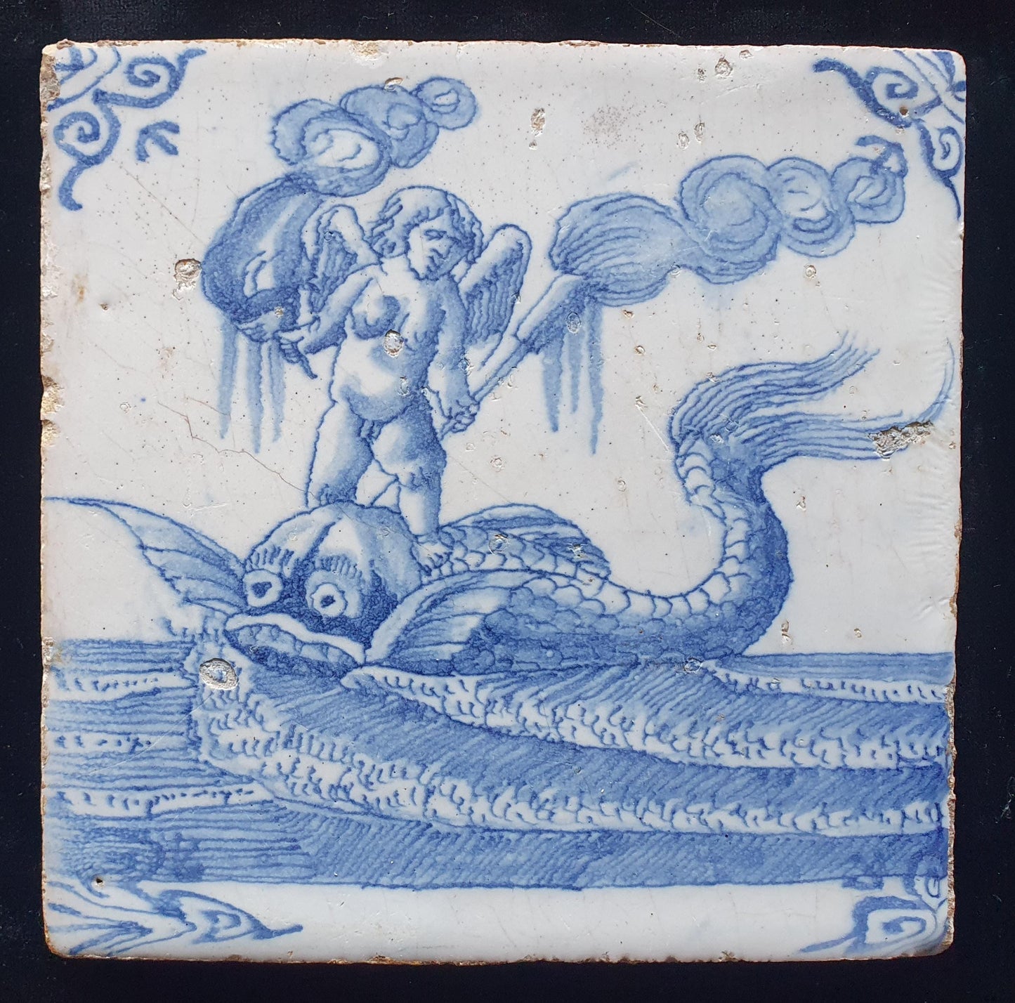 Deze antieke Delftse tegel dateert van rond 1670 en toont een putti op een monsterachtige dolfijn staat, verzameltegel.