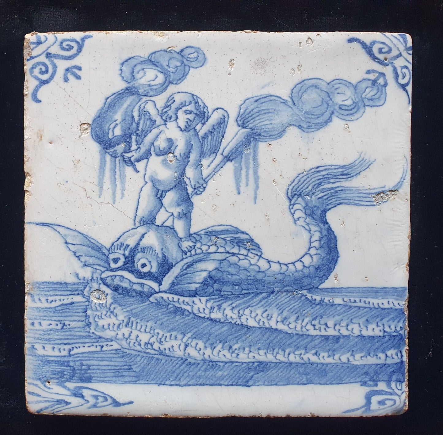 Deze antieke Delftse tegel dateert van rond 1670 en toont een putti op een monsterachtige dolfijn staat, verzameltegel.