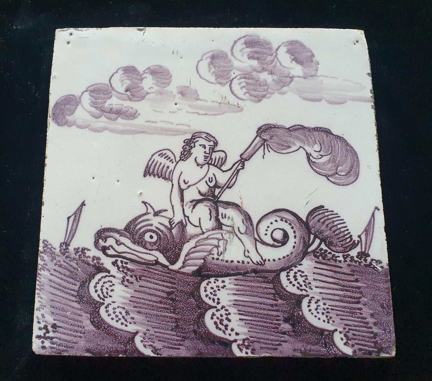 Deze antieke Delftse tegel dateert van rond 1750 en toont een putti op een monsterachtige dolfijn zit, verzameltegel.