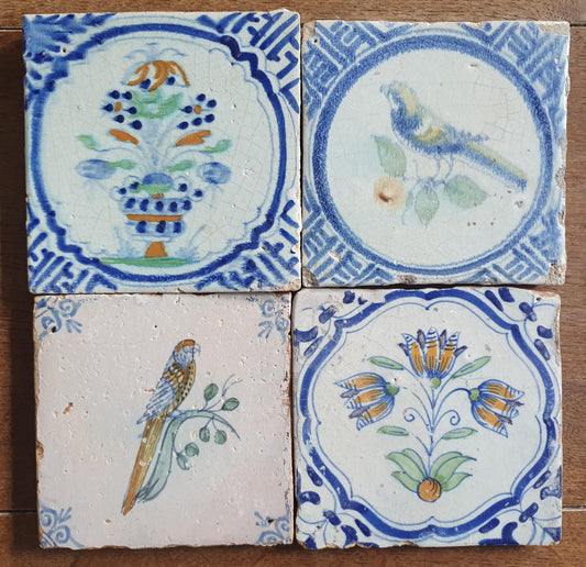 4 x Antique Delft tiles with colorful flowers and birds. The tiles are decorated with 'lily' corner motifs.