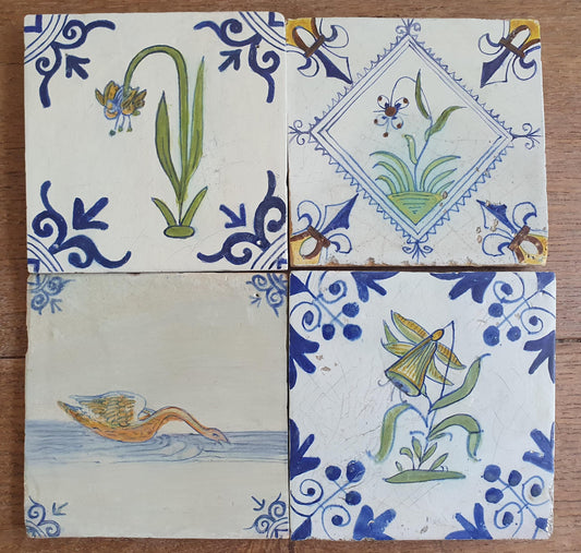 4 x Antique Delft tiles with colorful flowers and birds. The tiles are decorated with 'oxhead' corner motifs.
