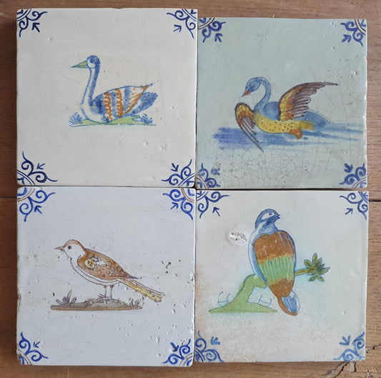 4 x Antique Delft tiles with colorful  birds. The tiles are decorated with 'oxhead' corner motifs.