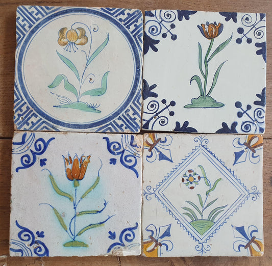 4 x Antique Delft tiles with colorful flowers . The tiles are decorated with 'oxhead'-lily corner motifs.