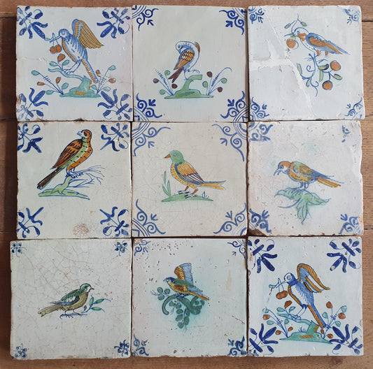 9 x Antique Delft tiles with colorful  birds. The tiles are decorated with 'oxhead' corner motifs.