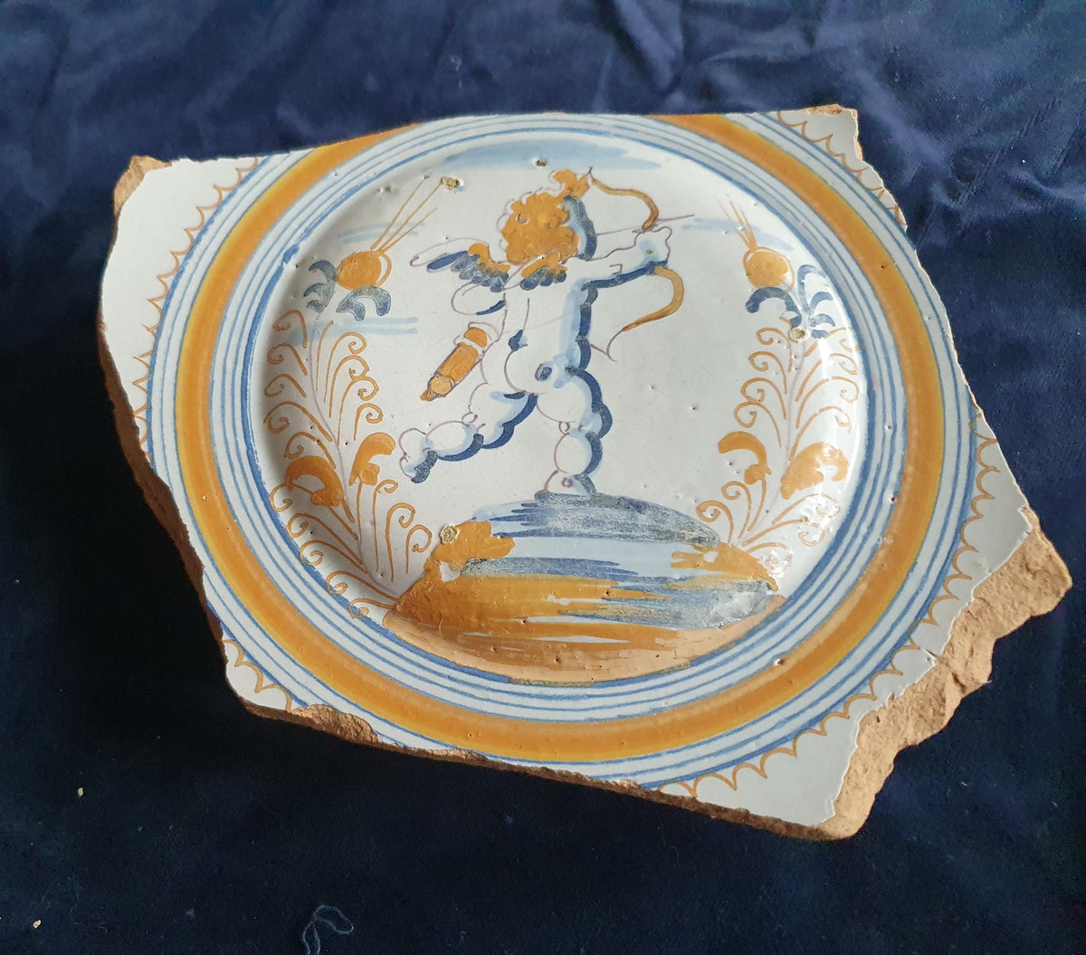 A rare, large shard from a plate, featuring a depiction on the base of a striding putto with a bow and arrow. 17th