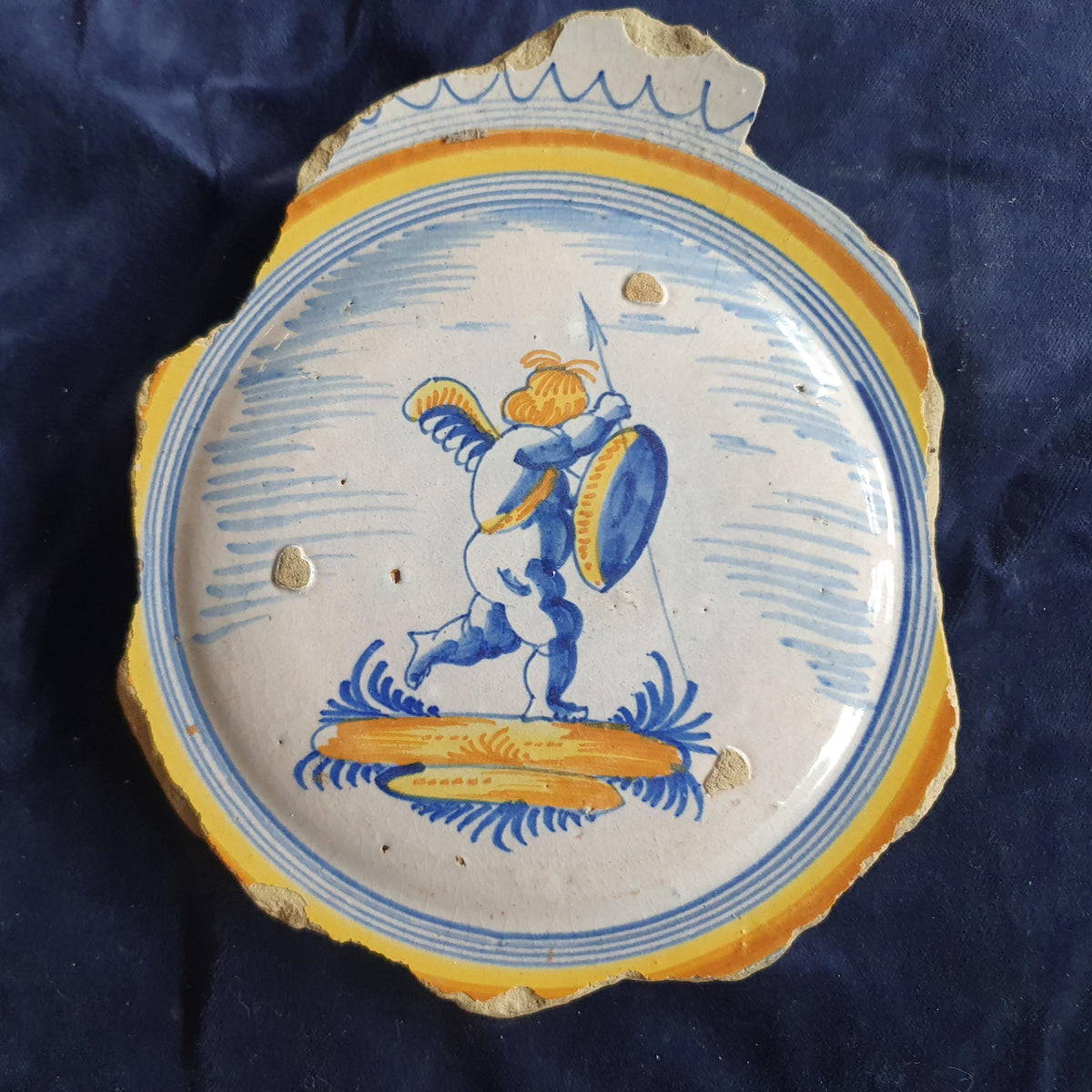 A Large rare majolica fragment depicting a striding putto on base, with spear and shield and a sash draped over the shoulder. 20 x 16 cm.
