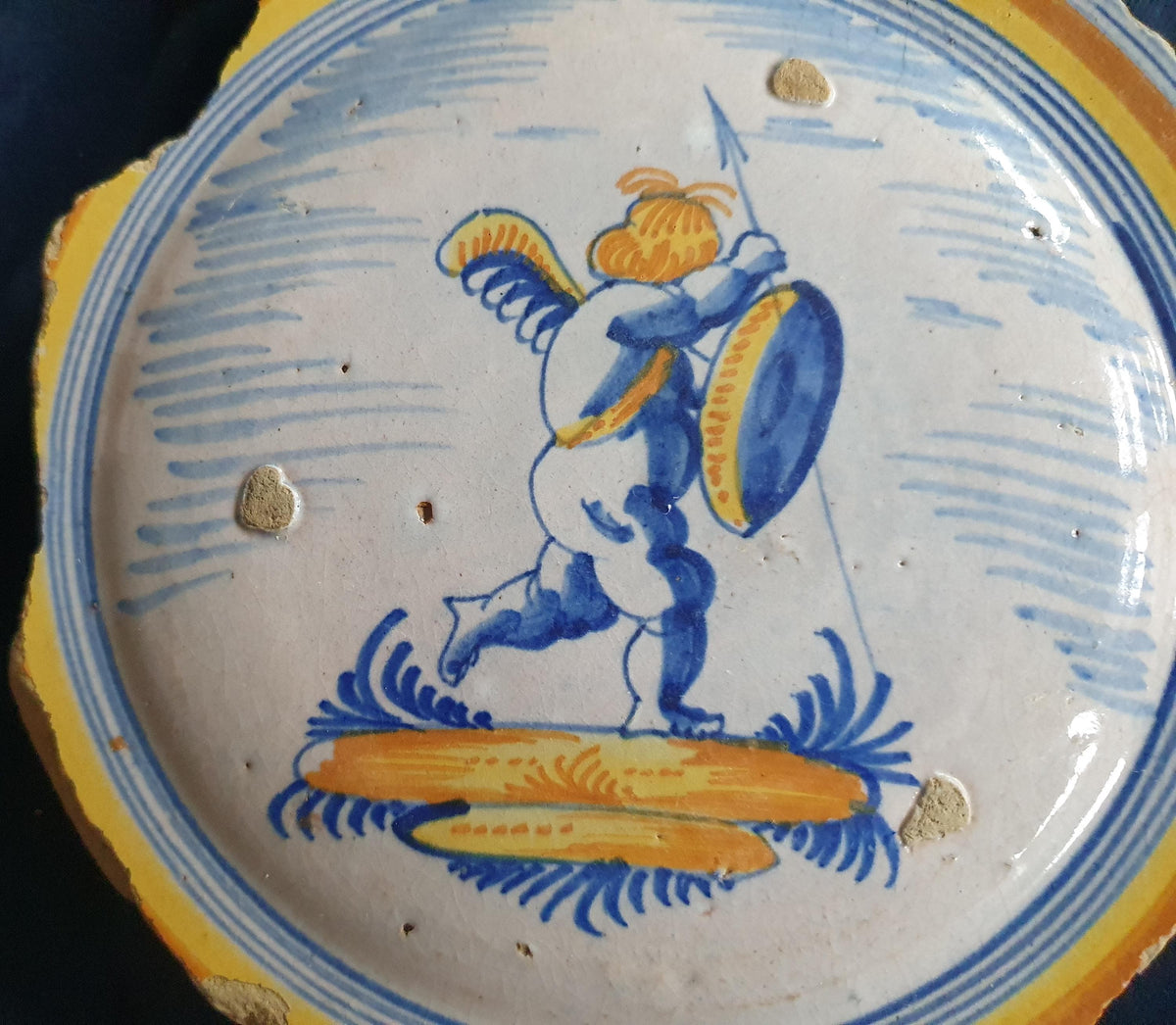 A Large rare majolica fragment depicting a striding putto on base, with spear and shield and a sash draped over the shoulder. 20 x 16 cm.