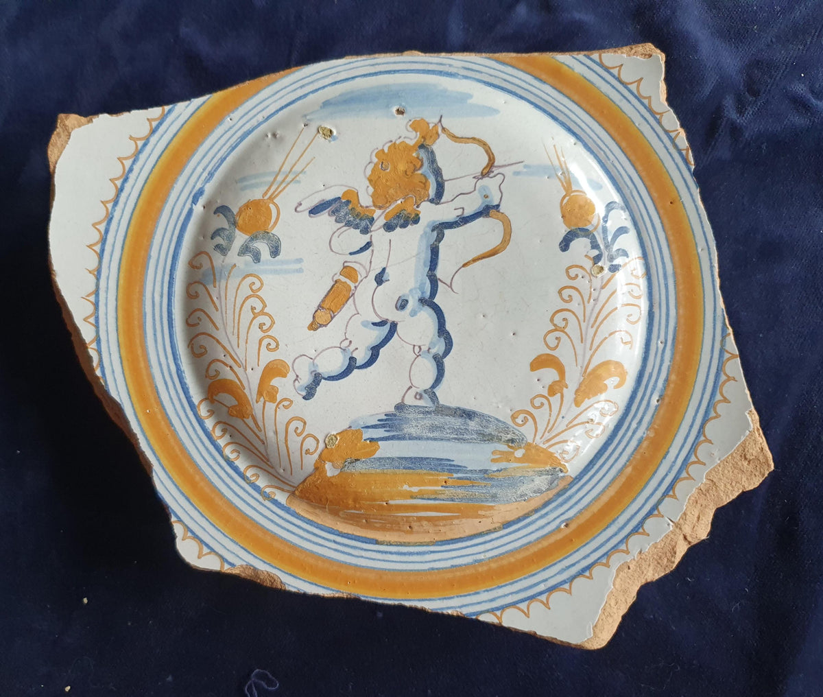 A rare, large shard from a plate, featuring a depiction on the base of a striding putto with a bow and arrow. 17th