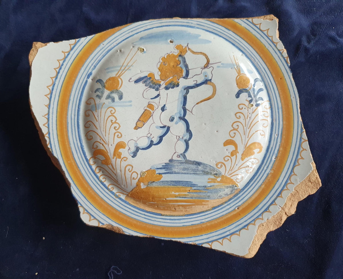 A rare, large shard from a plate, featuring a depiction on the base of a striding putto with a bow and arrow. 17th
