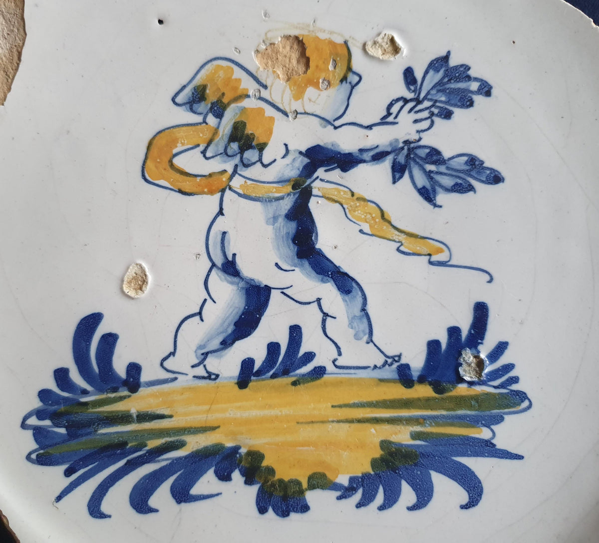 A rare, large shard from a plate, featuring a depiction on the base of a striding putto with a laurel wreath. 17th.
