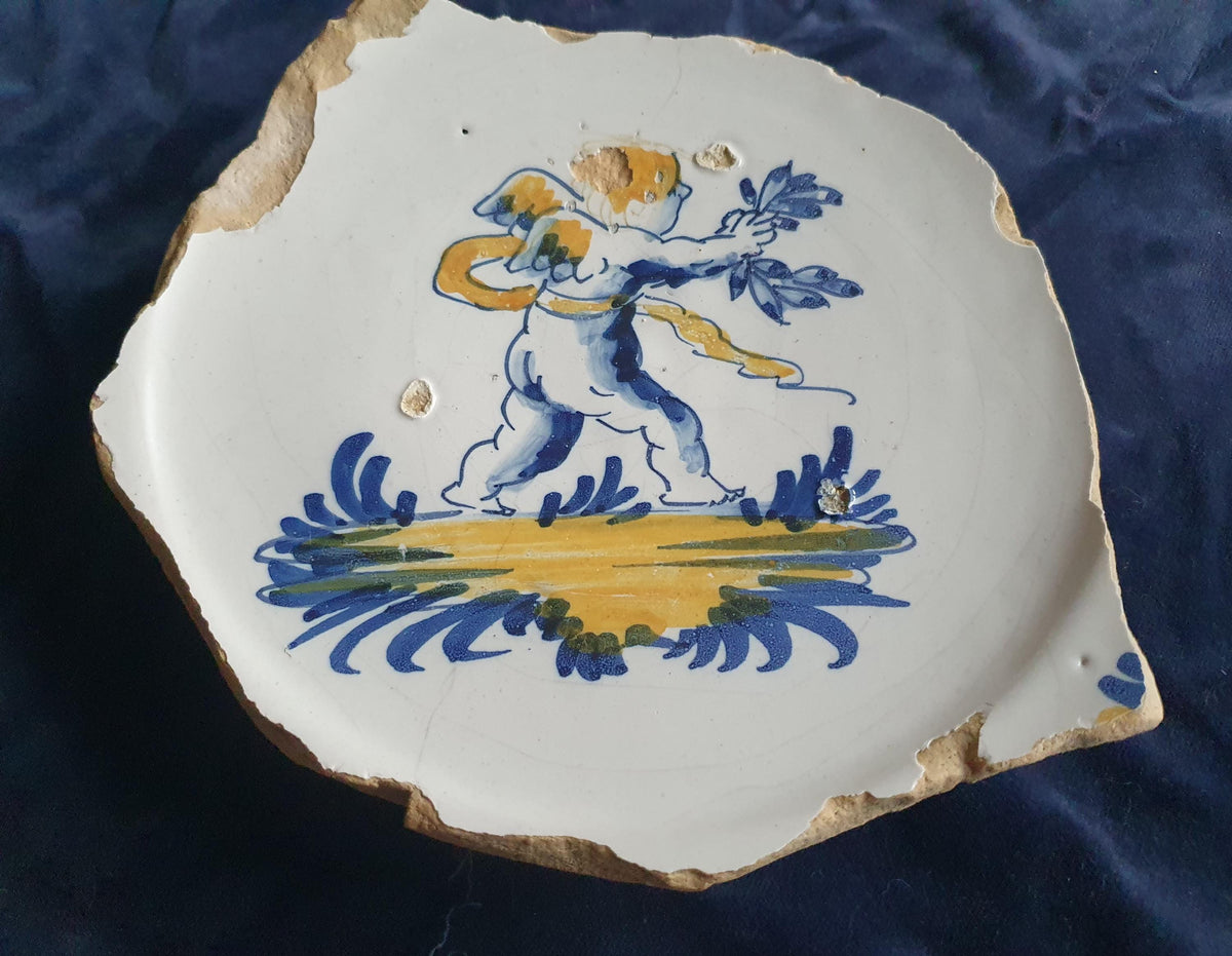A rare, large shard from a plate, featuring a depiction on the base of a striding putto with a laurel wreath. 17th.