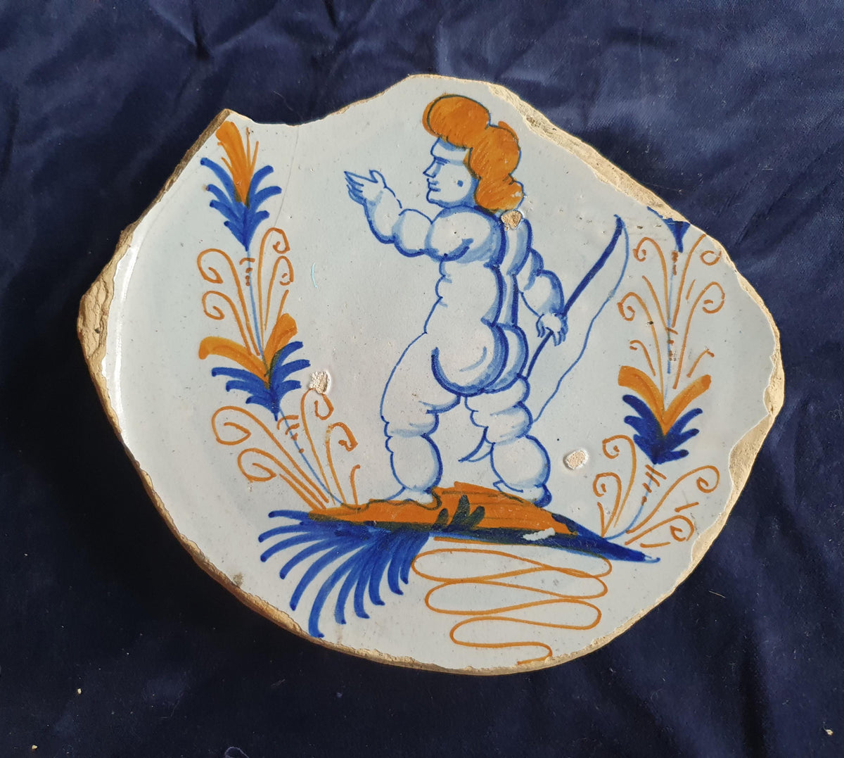 A rare, large shard from a plate, featuring a depiction on the base of a striding putto with a bow . 17th